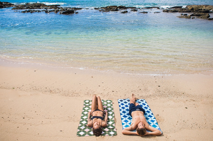 Άντρας και γυναίκα ξαπλωμένοι πάνω σε πετσέτες στην παραλία