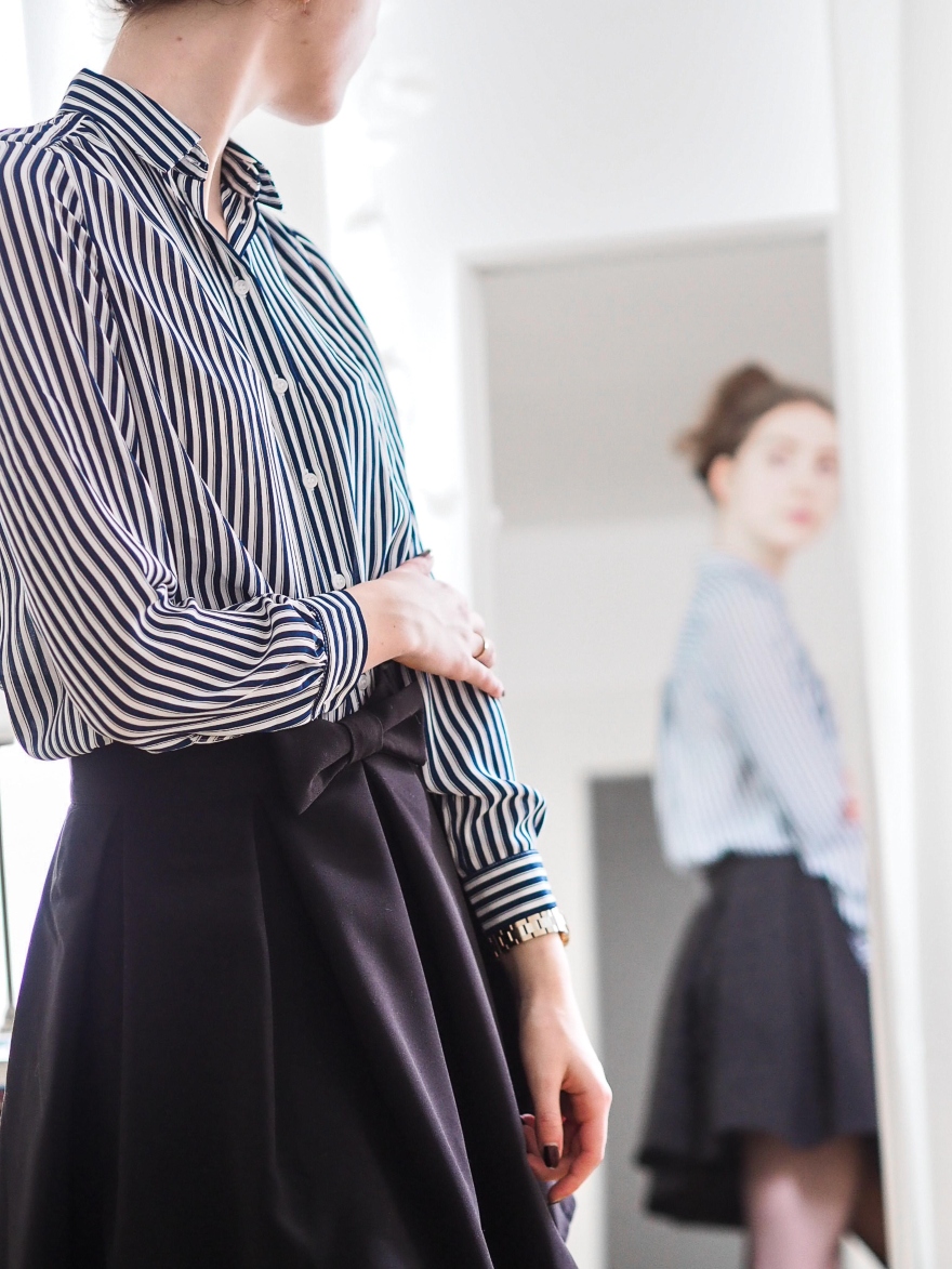 Κορίτσι μπροστά σε καθρέφτη με φούστα και ριγέ πουκάμισο